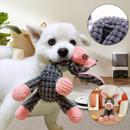 Peluche pour chien en forme d'âne tenue dans la gueule par un chien heureux
